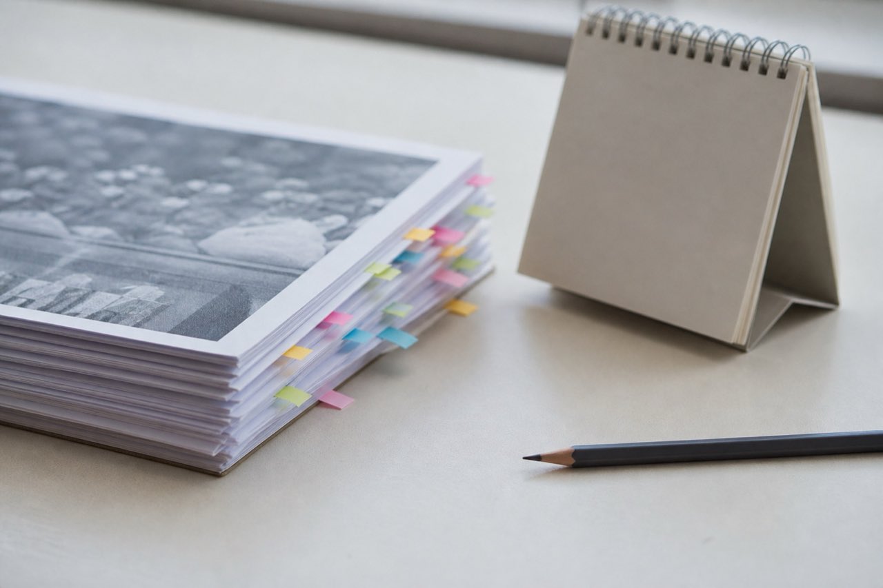 A stack of source printouts with colored paper tabs and a calendar page with all text illegible